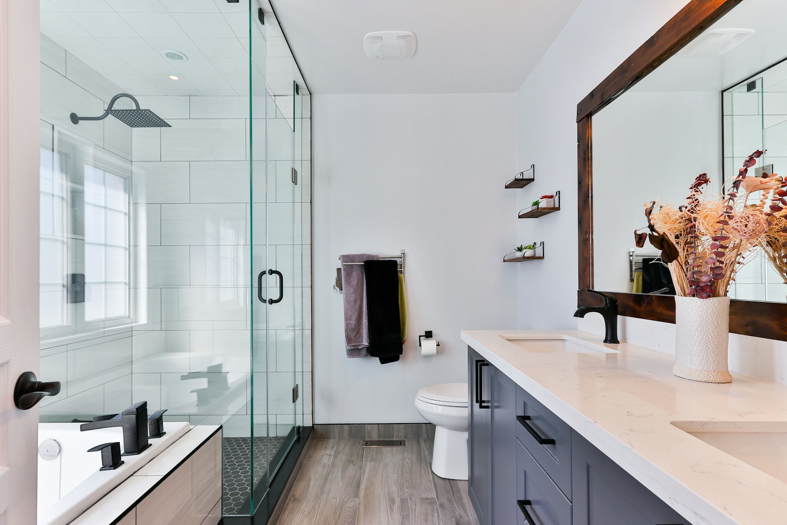 Renovated bathroom with glass shower, dark vanity and wood-look floor