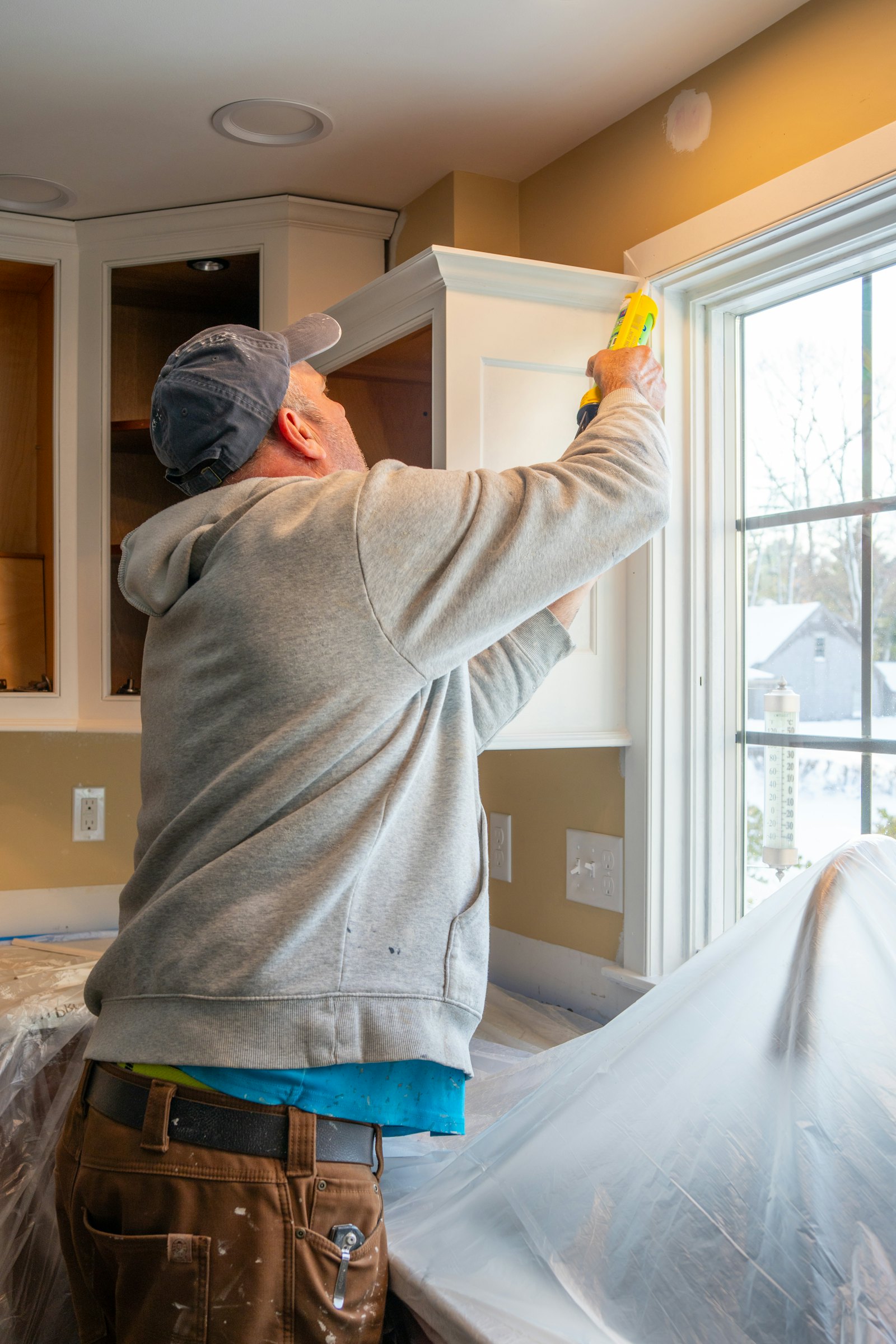 Installer sealing a window frame with caulk