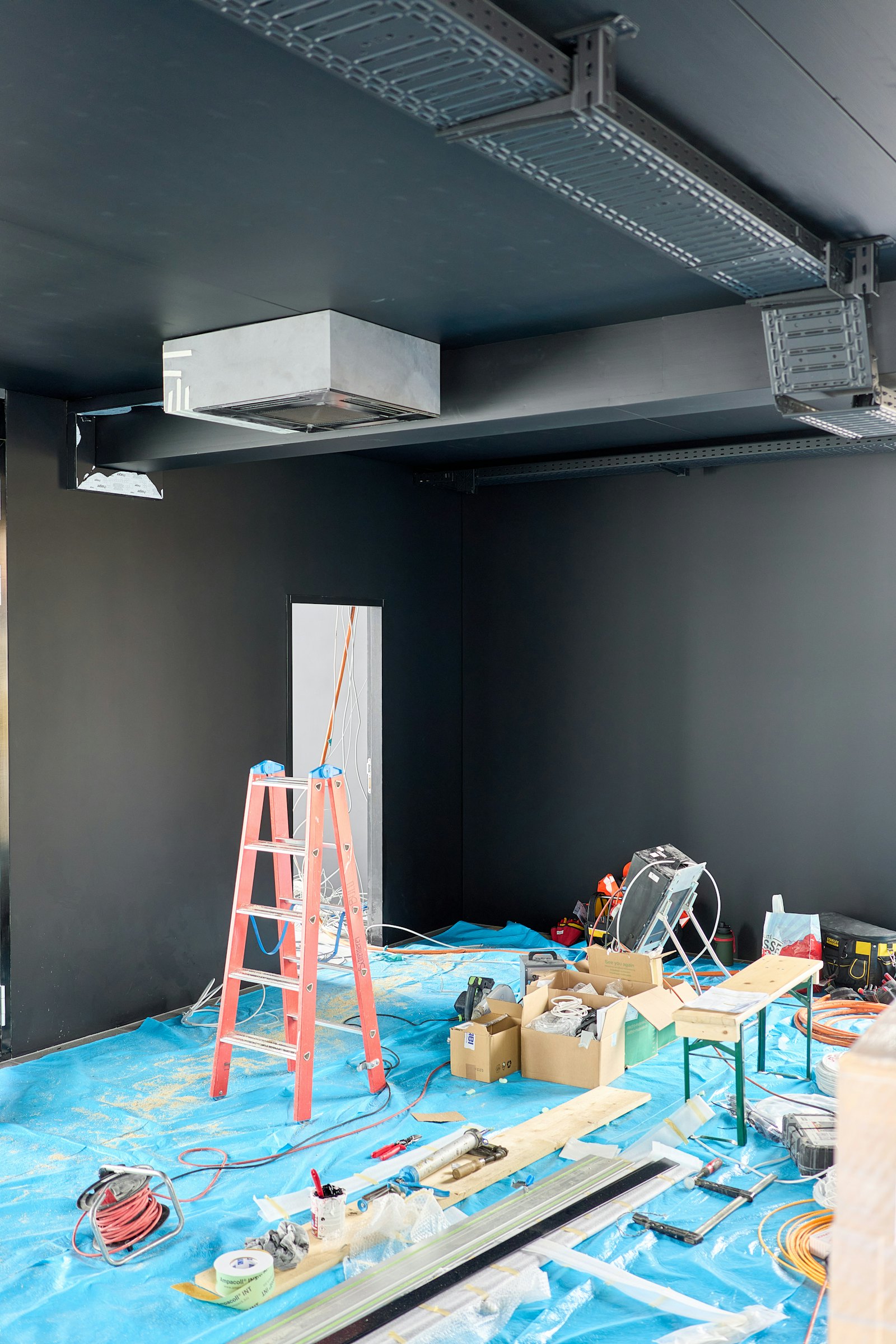 Room being drywalled with a step ladder and tools