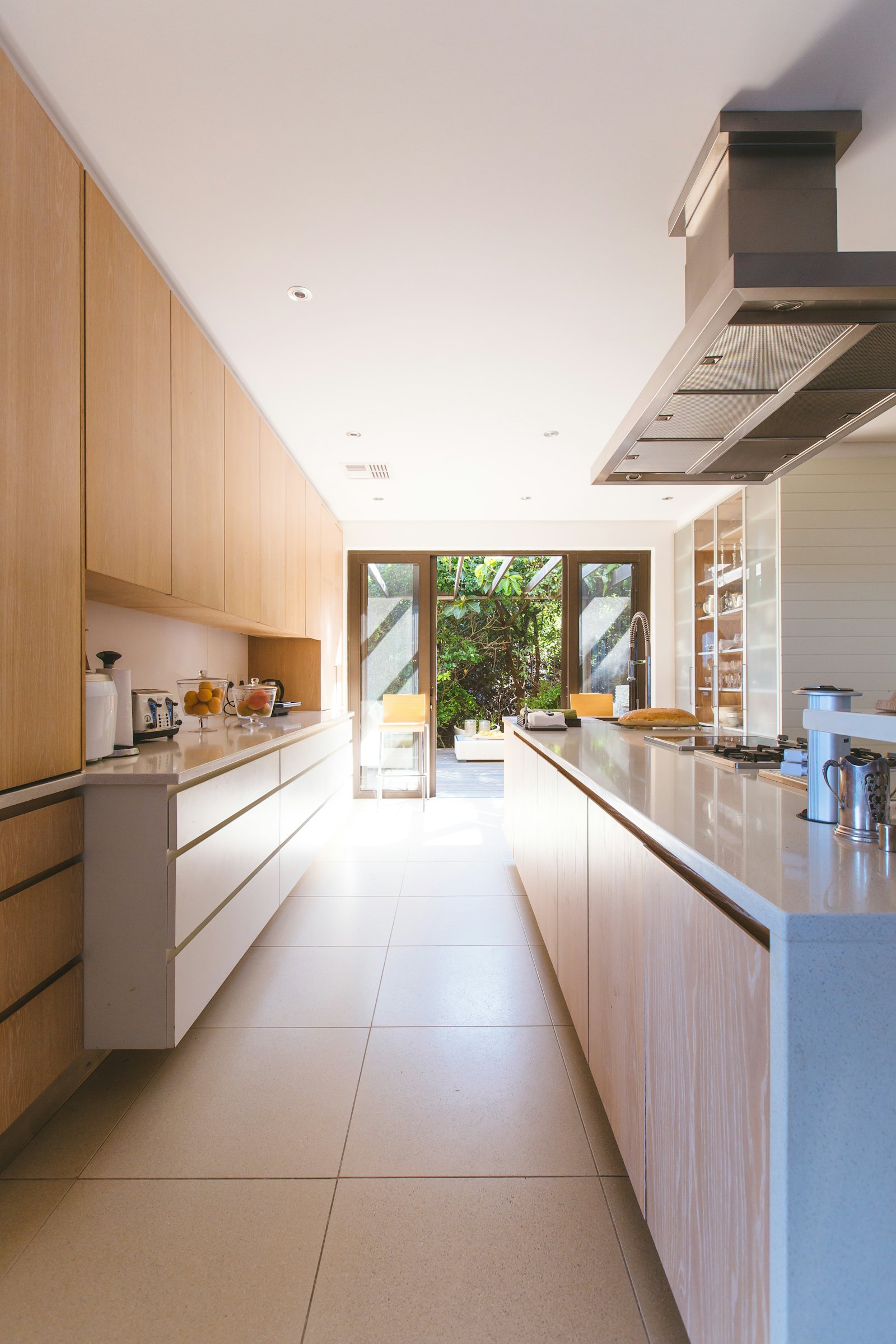 Long galley kitchen with wood cabinets opening to a patio