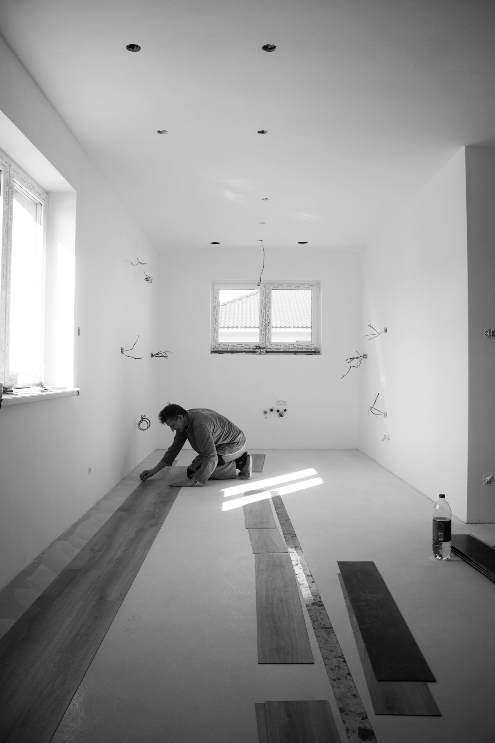 Installer laying plank flooring in an empty room