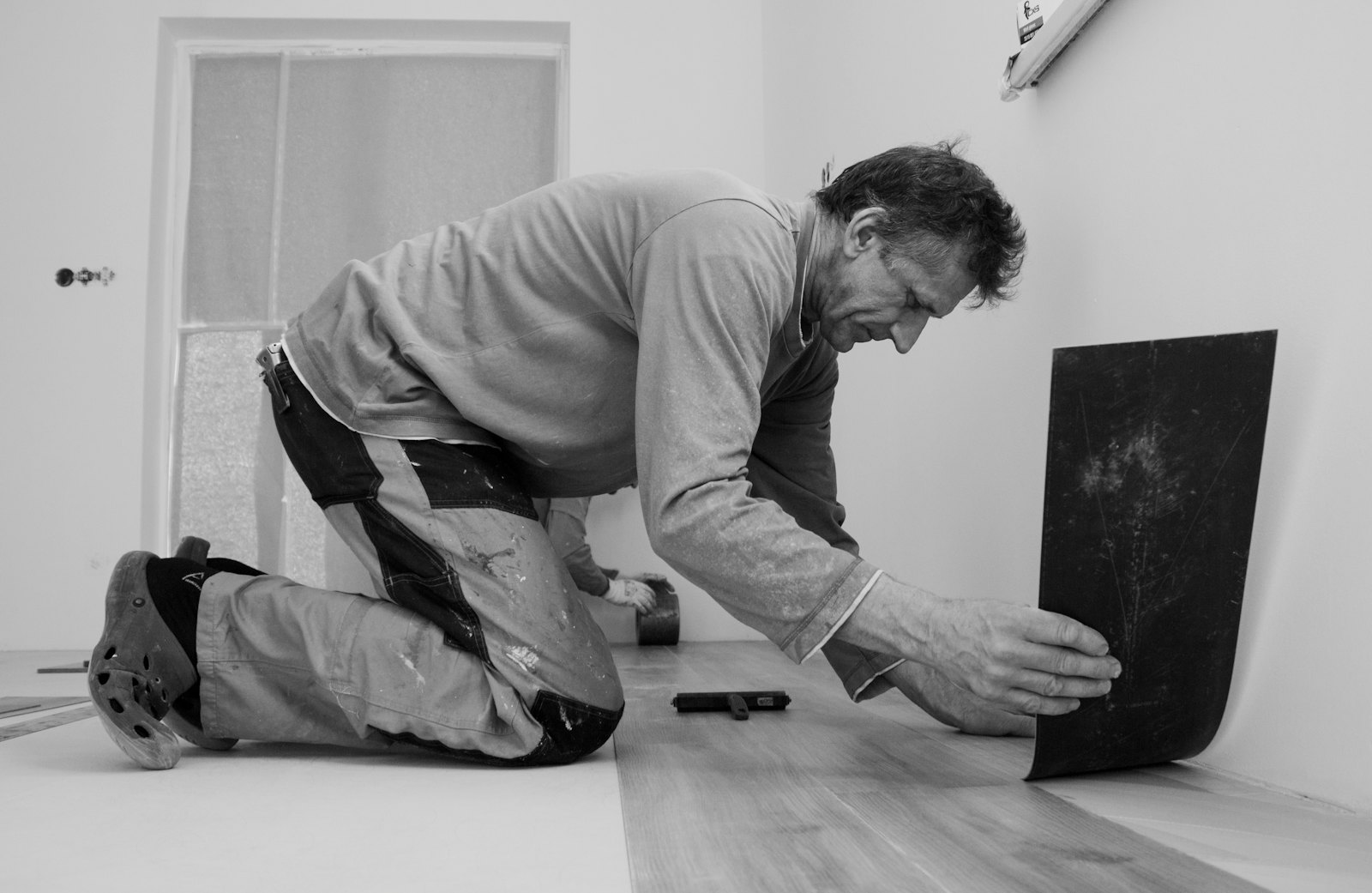 Installer kneeling to fit a floor plank